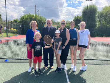 Wearing white tennis shoes, Anna Firth MP joins members of the Invicta Tennis Club to celebrate 75 years of the club’s existence